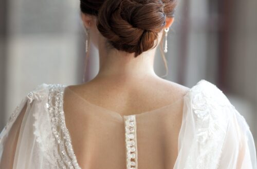 Bride in wedding dress from behind with glam bun hairstyle outdoors