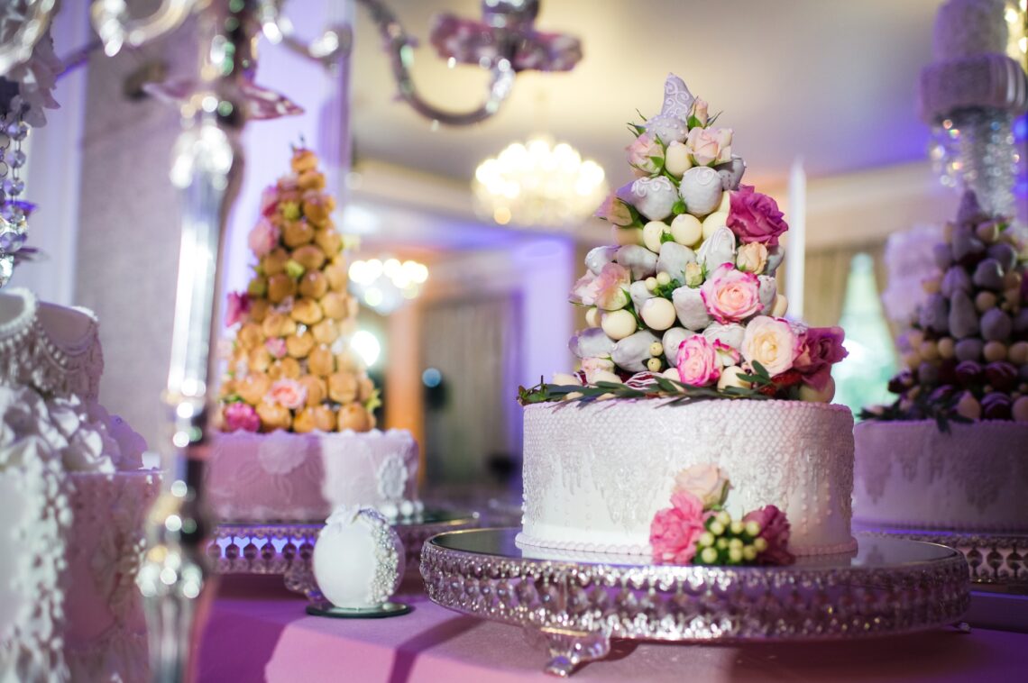 White wedding cake decorated with cream flowers on a stand