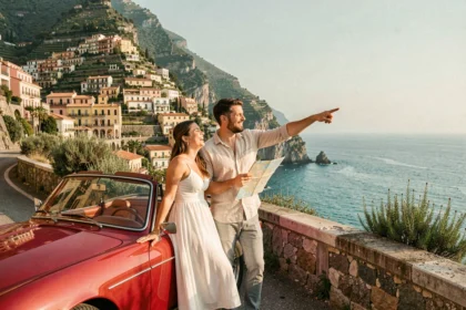 Couple de jeunes mariés en convertible rouge sur une route côtière d'Amalfi lors de leur road trip romantique en Italie